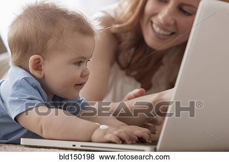 Caucasian mother and son using laptop on floor View Large Photo Image Stock Photo - Caucasian mother and son using laptop on floor. Fotosearch