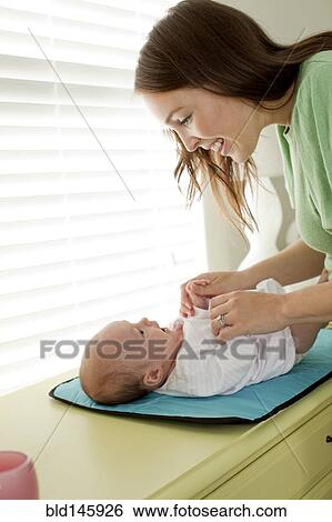 Caucasian mother changing baby daughter View Large Photo Image Stock Photograph - Caucasian mother changing baby daughter. Fotosearch