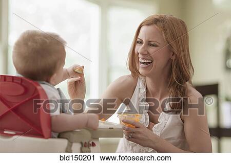 Stock Image - Caucasian mother feeding son. Fotosearch