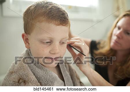 Stock Image - Caucasian mother giving son haircut. Fotosearch