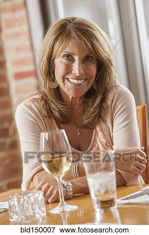 Stock Photo - Caucasian woman drinking wine in restaurant. Fotosearch