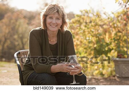Stock Photo - Caucasian woman drinking wine outdoors. Fotosearch