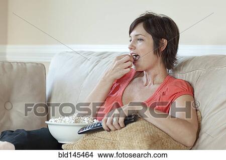 Caucasian woman eating popcorn and watching television View Large Photo Image Picture - Caucasian woman eating popcorn and watching television. Fotosearch