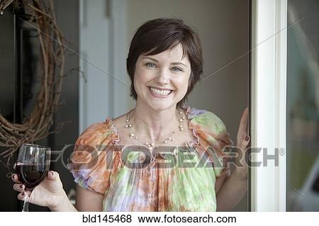 Caucasian woman holding wine glass and opening door View Large Photo Image Stock Photo - Caucasian woman holding wine glass and opening door. Fotosearch