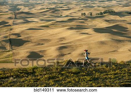 Stock Image - Caucasian woman running in remote area. Fotosearch