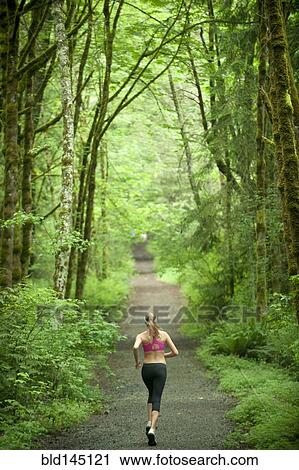 Stock Image - Caucasian woman running on remote path. Fotosearch