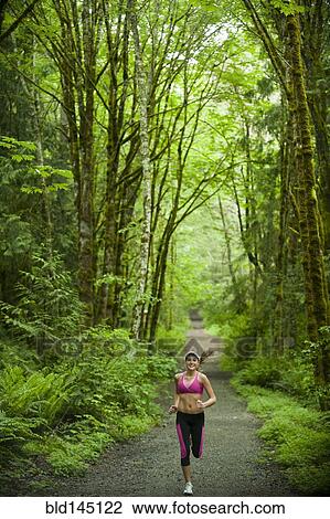 Stock Image - Caucasian woman running on remote path. Fotosearch