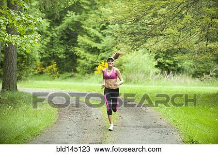 Stock Image - Caucasian woman running on remote path. Fotosearch