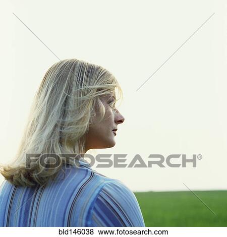 Stock Photo - Caucasian woman standing in green field. Fotosearch