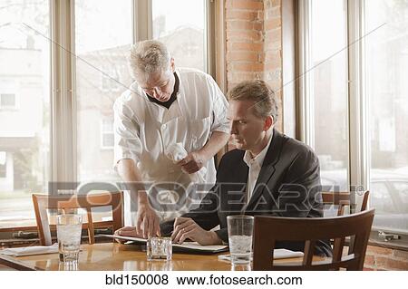 Stock Photo - Chef talking to customer about the menu in restaurant. Fotosearch
