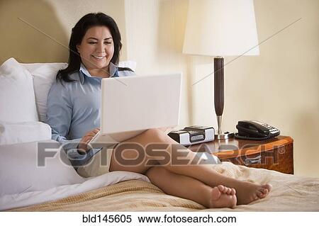 Chilean businesswoman sitting on bed using laptop View Large Photo Image Stock Photography - Chilean businesswoman sitting on bed using laptop. Fotosearch