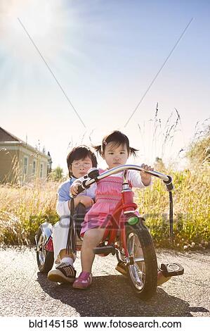 Stock Photo - Chinese brother and sister riding tricycle. Fotosearch