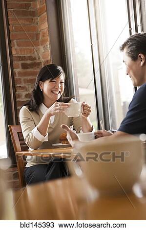 Stock Image - Chinese couple relaxing in cafe. Fotosearch