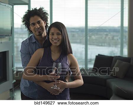 Stock Photo - Couple drinking red wine in living room. Fotosearch