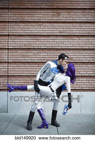 Stock Image - Couple in superhero costumes kissing. Fotosearch
