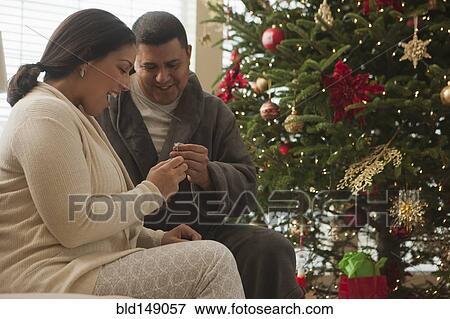 Couple opening gifts on Christmas morning View Large Photo Image Stock Photo - Couple opening gifts on Christmas morning. Fotosearch