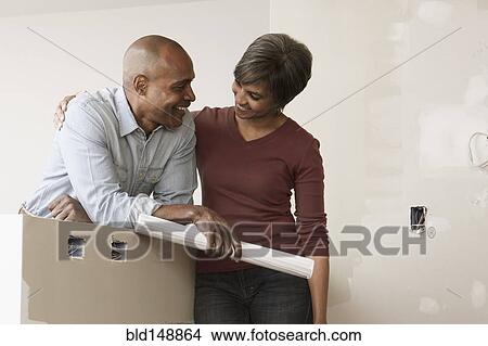 Couple standing in unfinished room with blueprints View Large Photo Image Picture - Couple standing in unfinished room with blueprints. Fotosearch