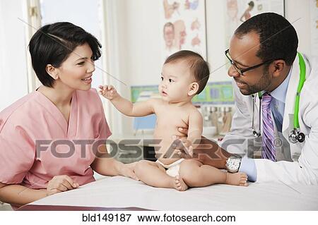 Stock Photo - Doctor and nurse examining baby in doctor's office. Fotosearch