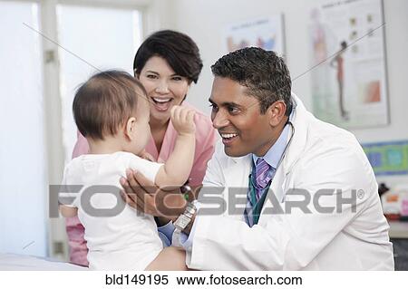 Stock Photography - Doctor and nurse examining baby in doctor's office. Fotosearch
