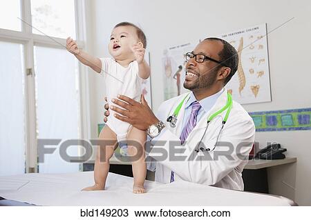 Stock Image - Doctor examining baby in doctor's office. Fotosearch