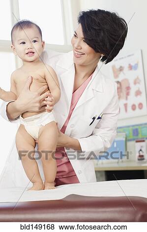 Stock Photo - Doctor examining baby in doctor's office. Fotosearch