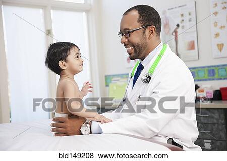 Stock Photo - Doctor examining baby in doctor's office. Fotosearch