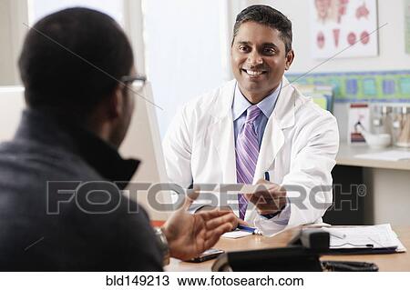 Stock Image - Doctor handing patient prescription in doctor's office. Fotosearch