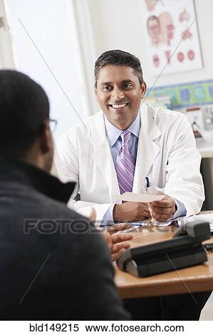 Stock Photography - Doctor handing patient prescription in doctor's office. Fotosearch
