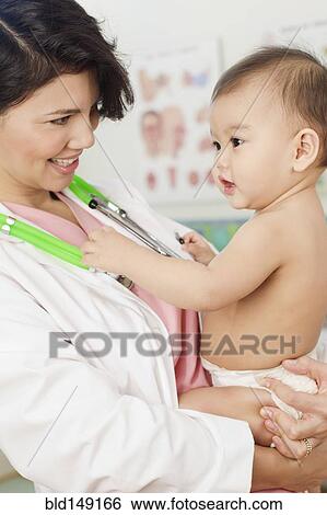 Stock Photograph - Doctor holding baby in doctor's office. Fotosearch