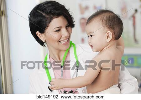 Doctor holding smiling baby in doctor's office View Large Photo Image Stock Image - Doctor holding smiling baby in doctor's office. Fotosearch