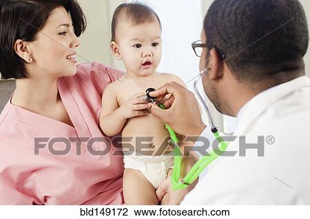 Stock Image - Doctor listening to baby's breathing in doctor's office. Fotosearch