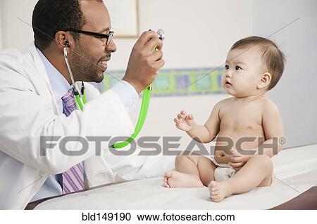 Stock Image - Doctor showing stethoscope to baby in doctor's office. Fotosearch