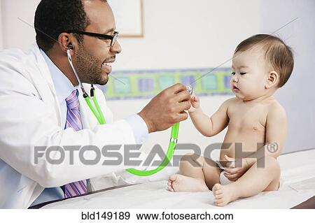 Stock Photo - Doctor showing stethoscope to baby in doctor's office. Fotosearch