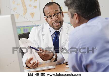 Stock Image - Doctor talking to patient in doctor's office. Fotosearch