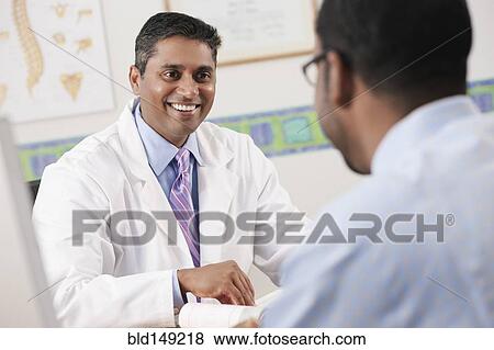 Stock Photo - Doctor talking to patient in doctor's office. Fotosearch