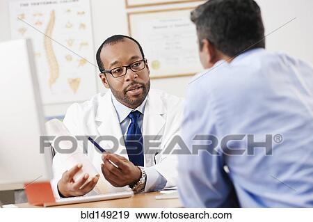 Stock Photo - Doctor talking to patient in doctor's office. Fotosearch