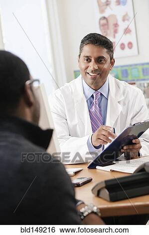 Stock Photograph - Doctor talking to patient in doctor's office. Fotosearch