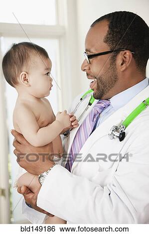 Doctor talking to serious baby in doctor's office View Large Photo Image Stock Photograph - Doctor talking to serious baby in doctor's office. Fotosearch