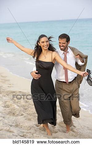 Stock Photo - Elegant couple walking on beach together. Fotosearch
