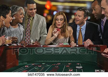 Stock Photography - Excited friends gambling at craps table in casino. Fotosearch