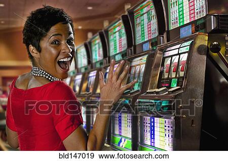 Excited mixed race woman playing slot machines in casino View Large Photo Image Stock Photo - Excited mixed race woman playing slot machines in casino. Fotosearch