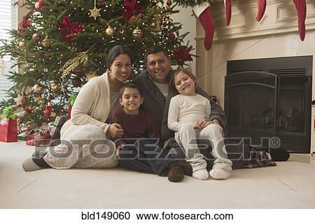 Stock Image - Family sitting on floor of living room on Christmas morning. Fotosearch