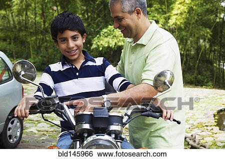 Stock Photograph - Father showing son motorcycle. Fotosearch