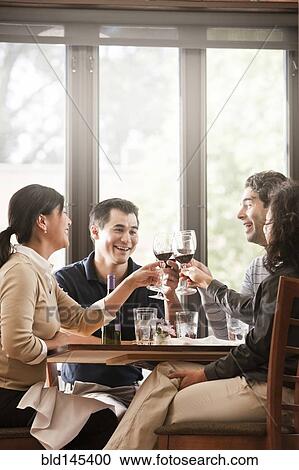 Stock Image - Friends drinking red wine together in restaurant. Fotosearch