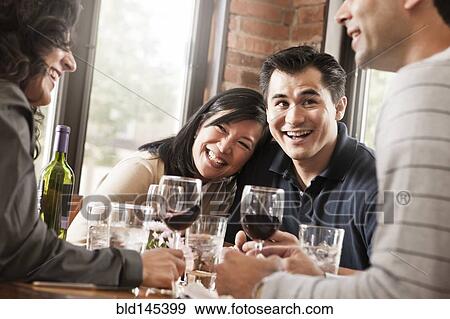 Stock Photo - Friends drinking red wine together in restaurant. Fotosearch