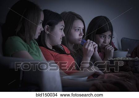 Friends eating popcorn and watching a movie View Large Photo Image Picture - Friends eating popcorn and watching a movie. Fotosearch