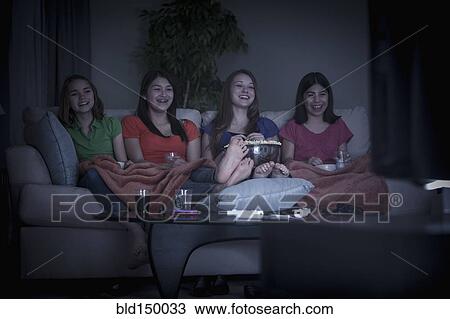 Friends eating popcorn and watching a movie View Large Photo Image Stock Image - Friends eating popcorn and watching a movie. Fotosearch