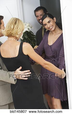 Stock Photo - Friends greeting couple arriving for party. Fotosearch
