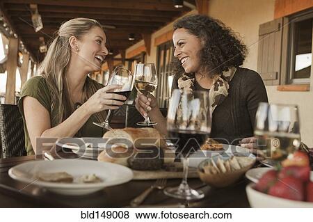 Stock Photo - Friends having lunch and drinking wine together. Fotosearch