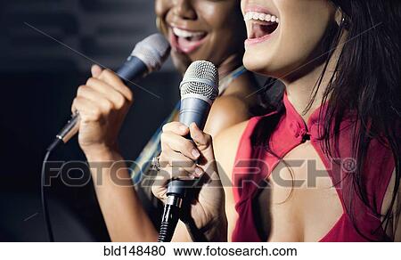 Friends singing karaoke in nightclub View Large Photo Image Stock Image - Friends singing karaoke in nightclub. Fotosearch